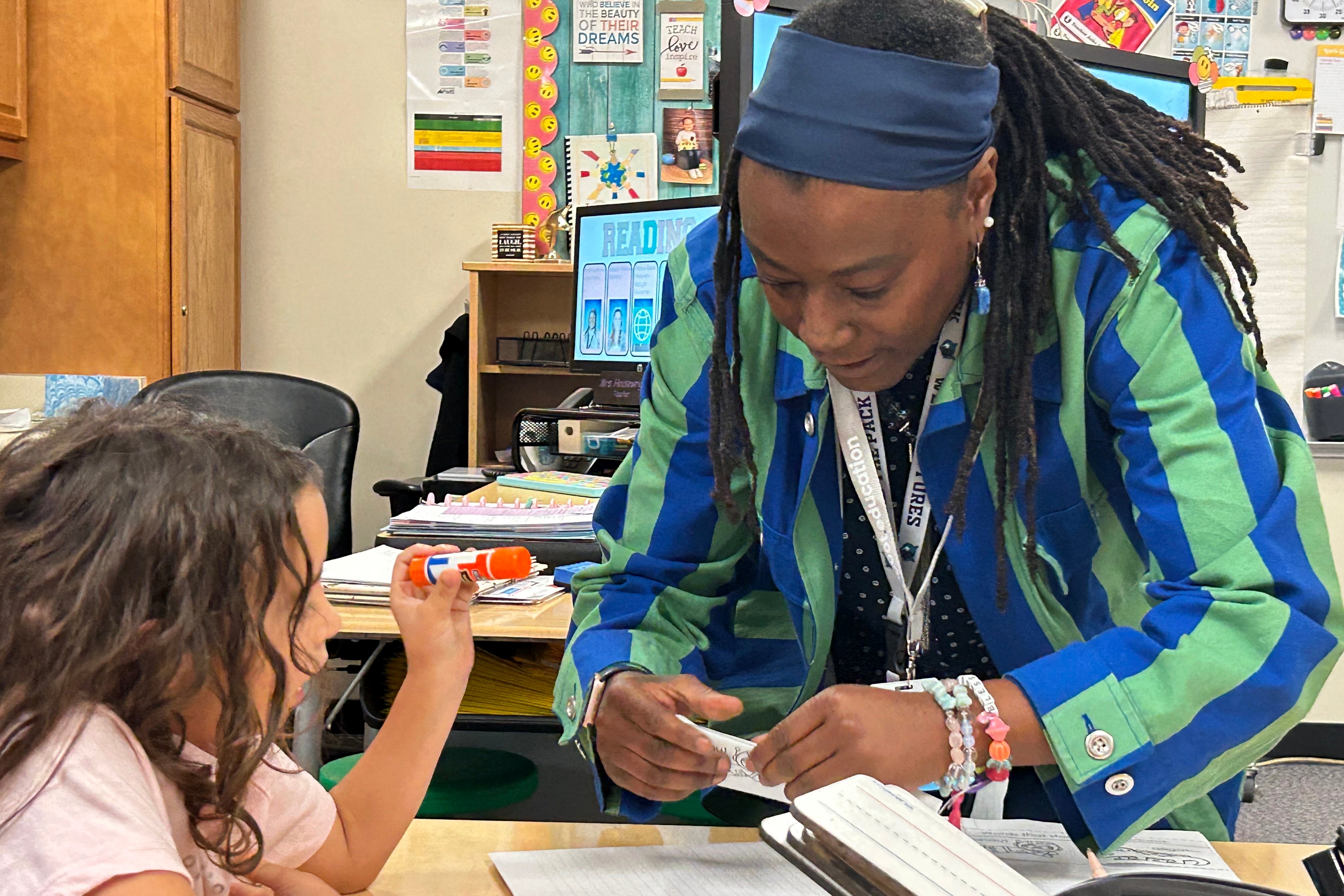 A photograph of a dry erase board and a poster with words and drawings in a classroom.