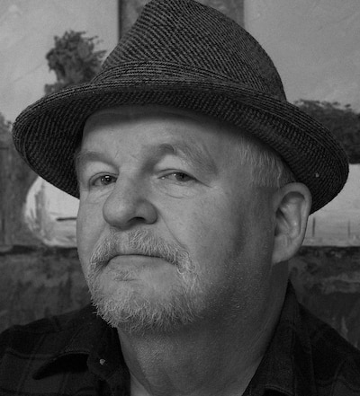 Black and white headshot of a man wearing a fedora.