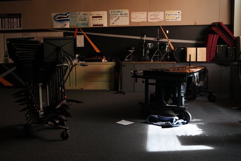 Chairs and equipment are stacked up in an empty classroom in deep shadow.