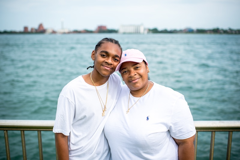 King Bethel poses with his mother, Netha Johnson. They are each wearing white shirts and are wearing gold necklaces, while Netha wears a pink Ralph Lauren hat.
