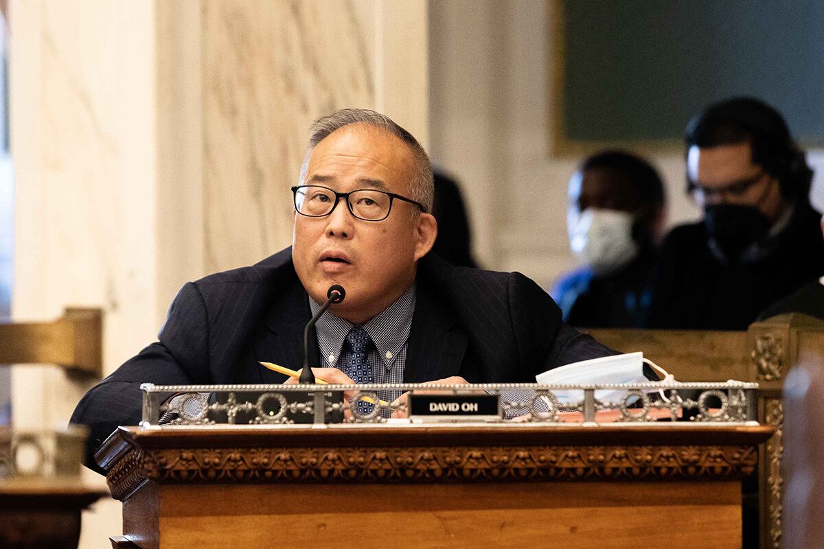 A Korean-American man in glasses speaks at a podium