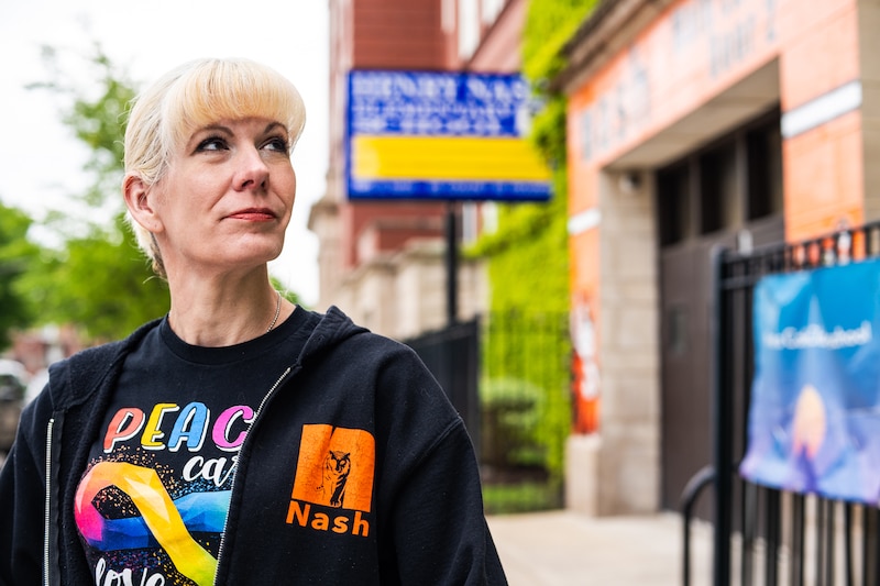 A white woman stands outside of a school building.