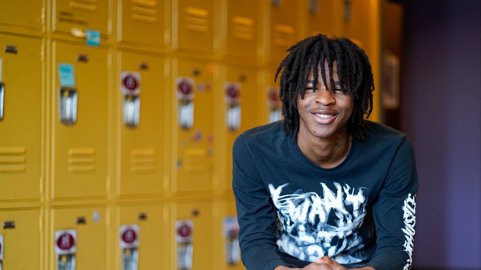 A portrait of a teenage in a blue shirt in front of yellow lockers