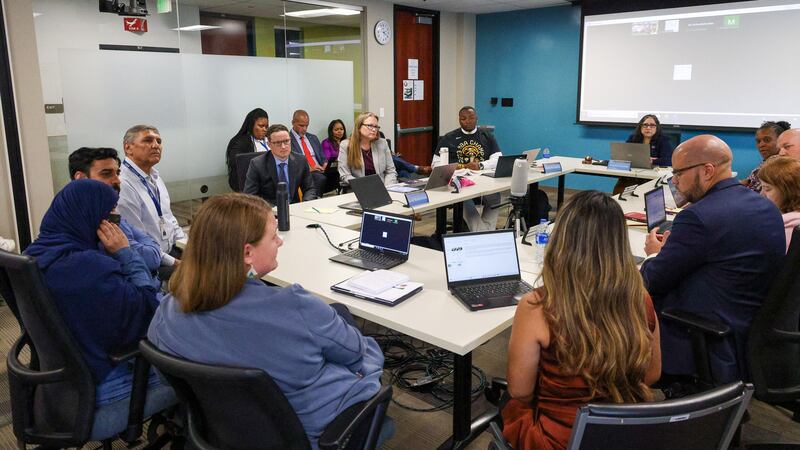 The Denver school board sits around a table in a room at Denver Public Schools headquarters.