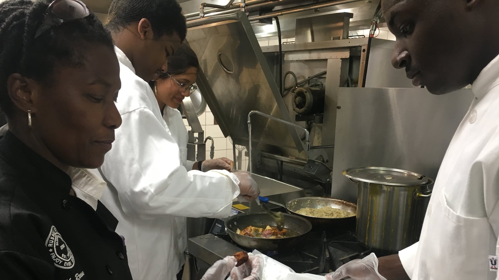 Marquita Reese, a math teacher at Frederick Douglass Academy for Young Men, works with students to cook vegetables grown in the school's greenhouse.