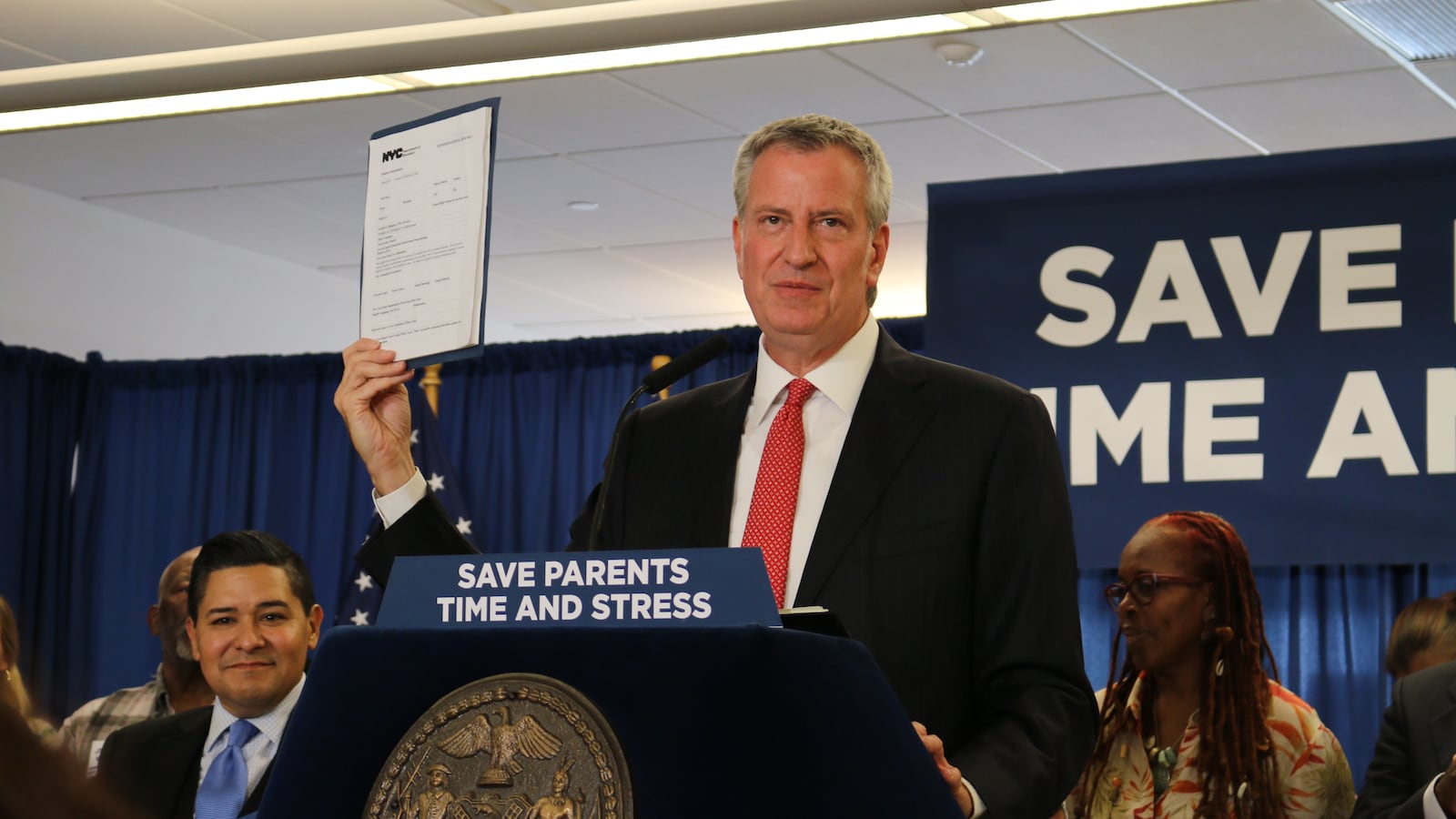 Mayor Bill de Blasio holds up a new application form while announcing changes to middle and high school admissions.