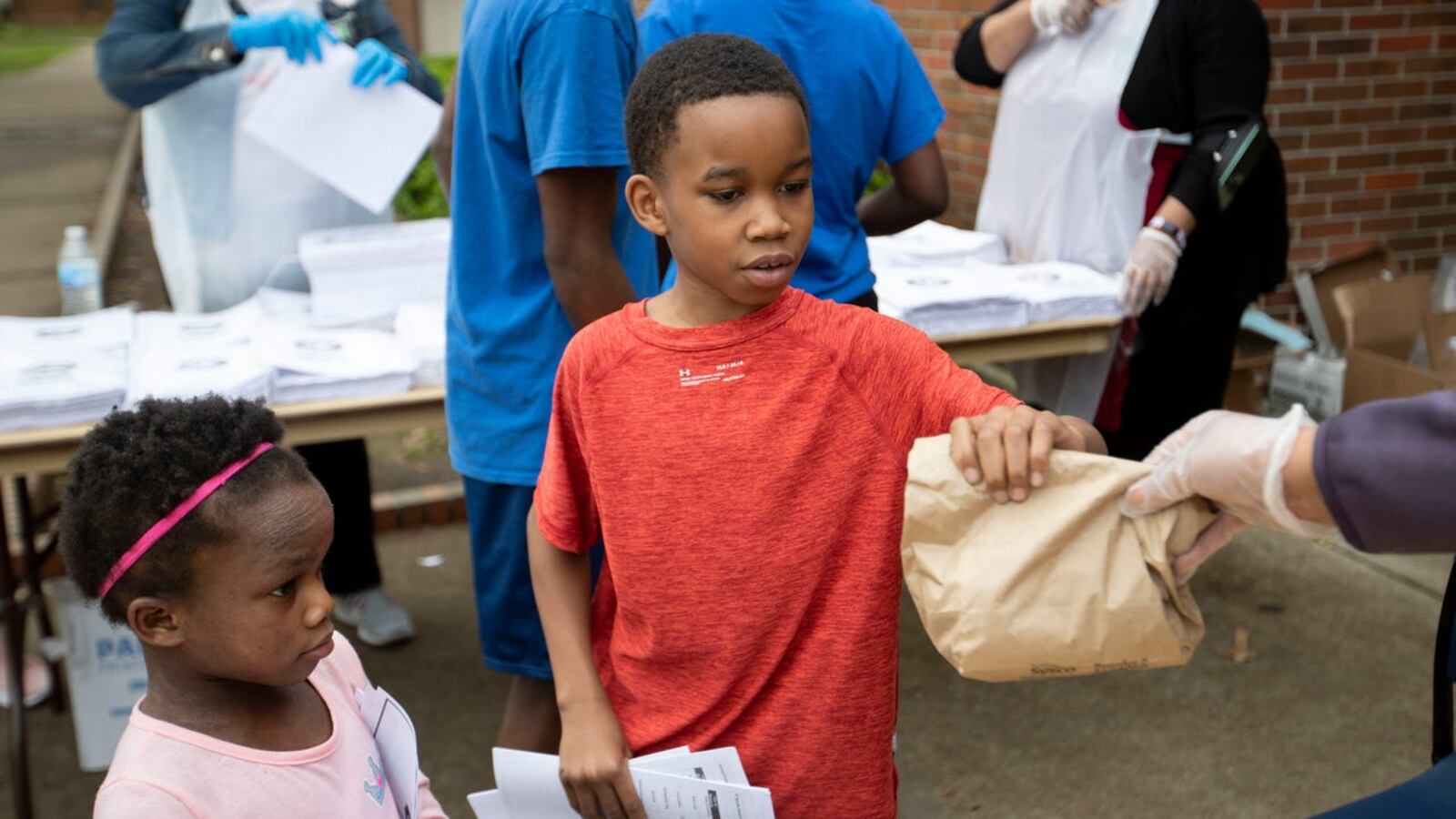 Ruby Buckner (from right) of the YMCA of Memphis and the Mid-South hands lunches to Camaree Hurd, 9, and his sister, Amani Hurd, 6, at Ed Rice Community Center in Memphis.