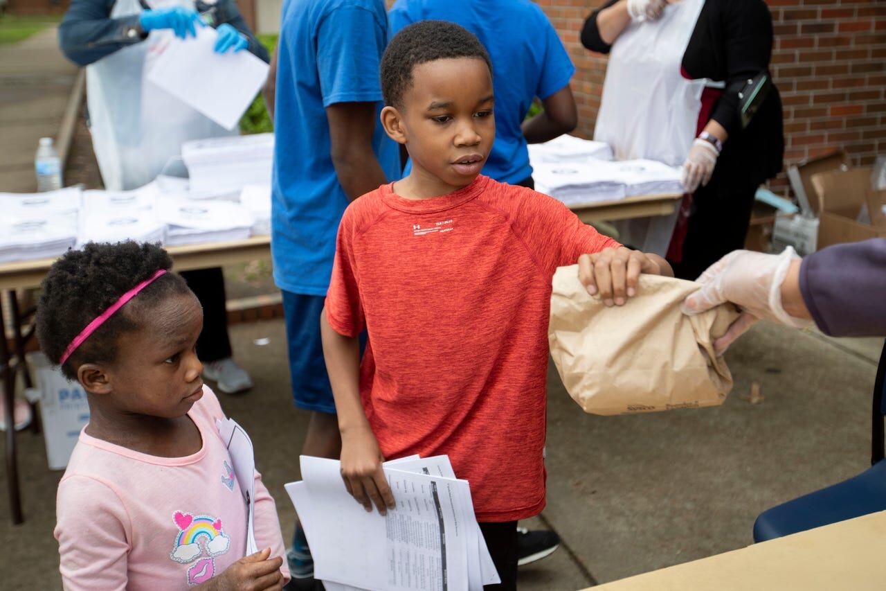 Ruby Buckner (from right) of the YMCA of Memphis and the Mid-South hands lunches to Camaree Hurd, 9, and his sister, Amani Hurd, 6, at Ed Rice Community Center in Memphis.