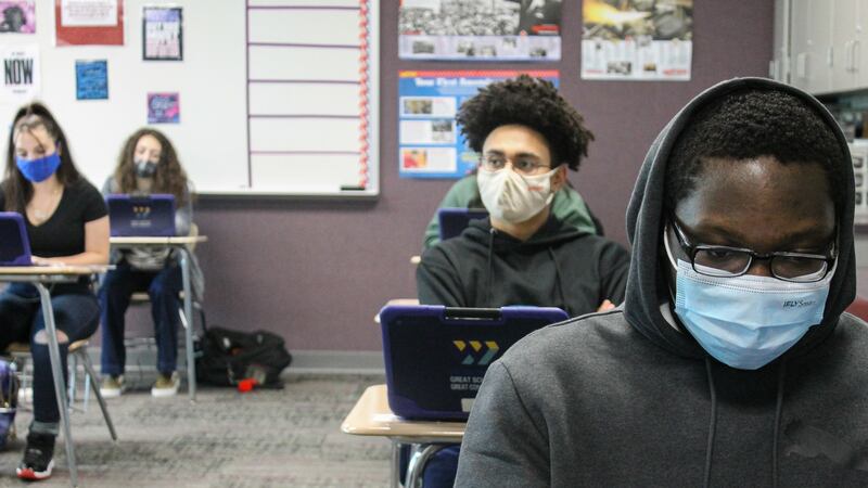 Four masked students sit at desks and look into laptops at Ben Davis High School in Indianapolis, Ind. on Friday, April 9, 2021.