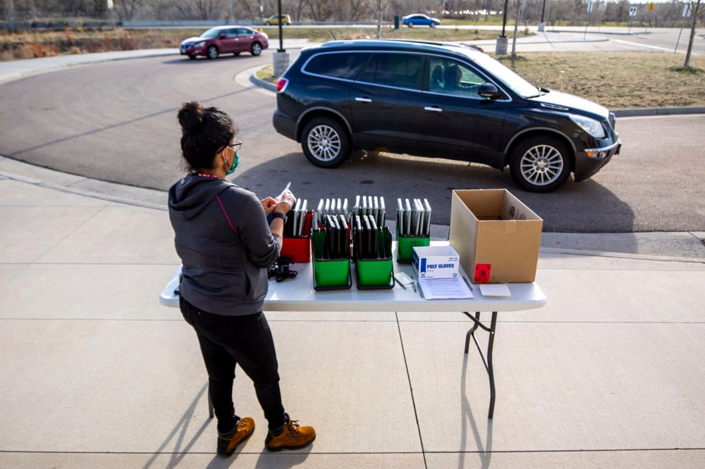 Staff distribute laptops to families at Denver’s Joe Shoemaker School on March 25, 2020, as schools prepare for remote learning.