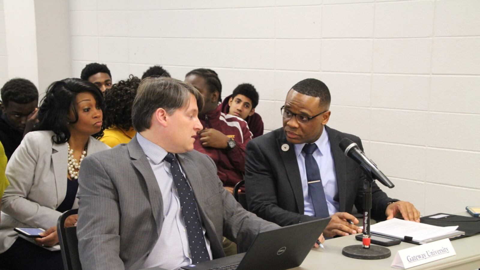Gateway University leader Sosepriala Dede (right) confers with an associate before a hearing.
