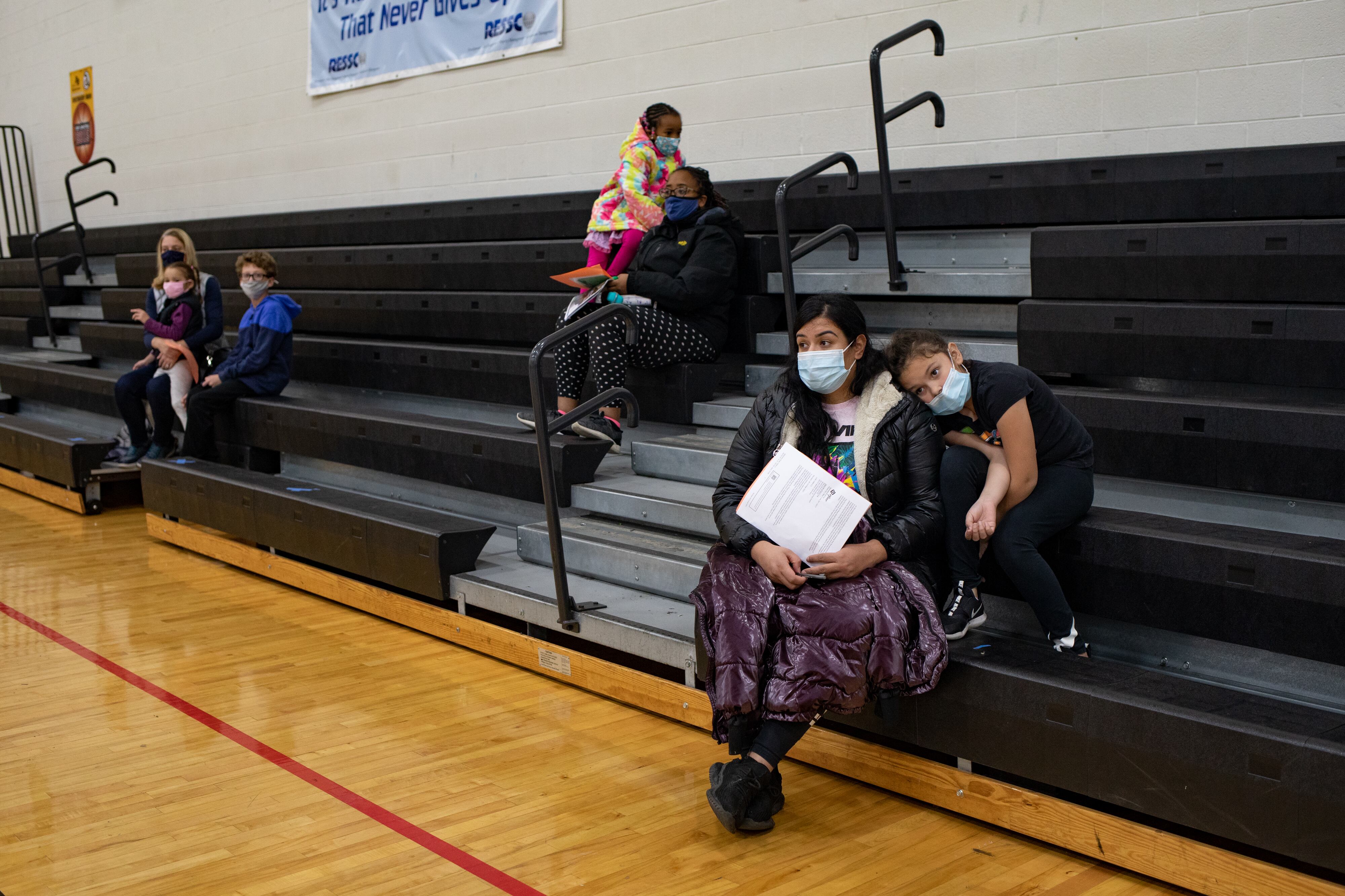 A mother waits with her daughter as she prepares to receive a dose of the Pfizer-BioNTech coronavirus vaccine.
