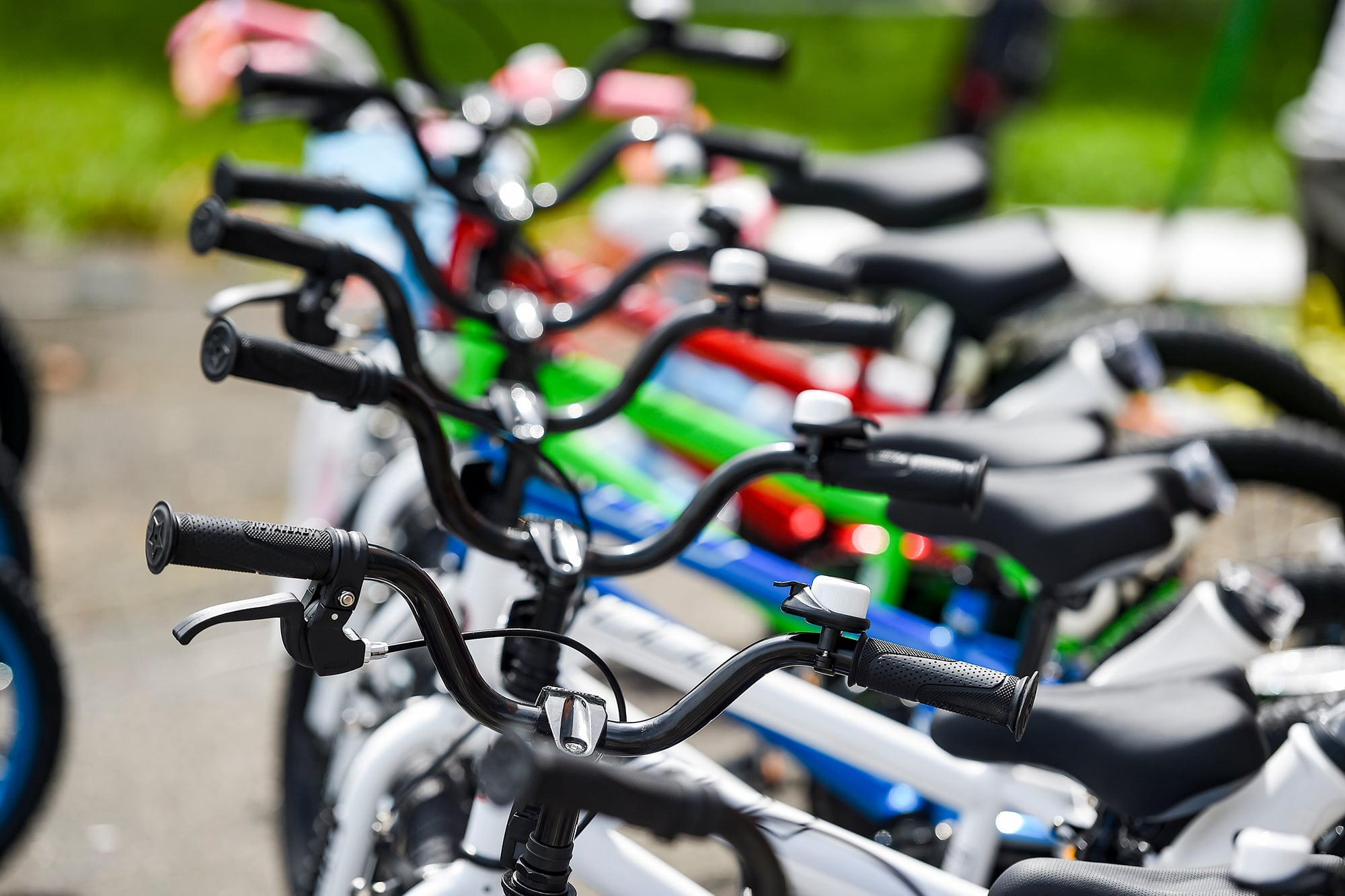 An up close photograph of handle bars of  bikes all in a row.