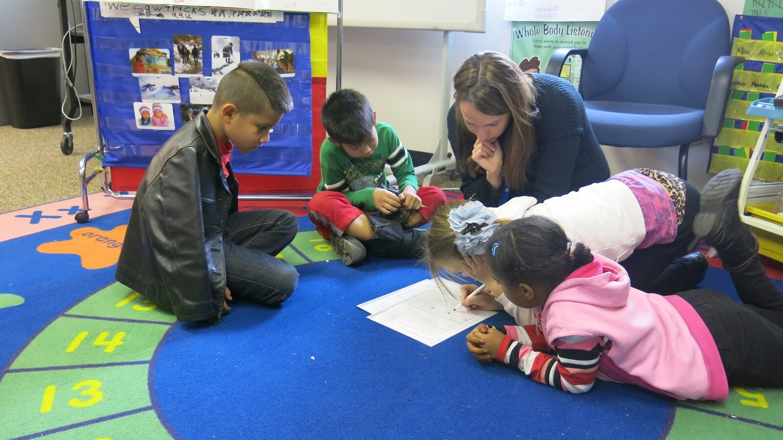 Third graders at Ellis Elementary sit on a bright blue and green rug to study English with ESL teacher Bree Roon. Each of the students in this group has a different native language, including Karen, Spanish, Russian/Turkish, Arabic, and Bosnian.