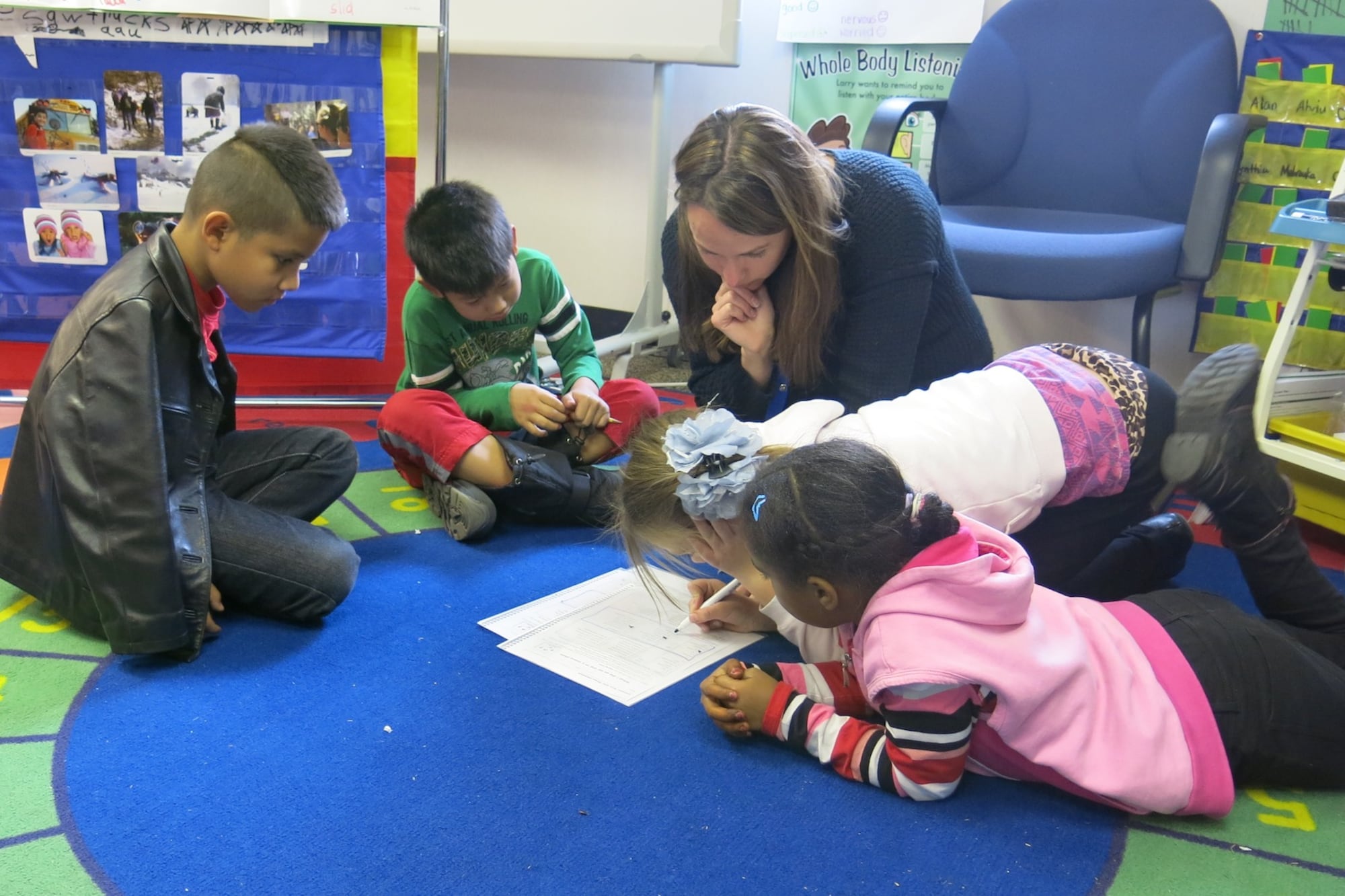 Third graders at Ellis Elementary sit on a bright blue and green rug to study English with ESL teacher Bree Roon. Each of the students in this group has a different native language, including Karen, Spanish, Russian/Turkish, Arabic, and Bosnian.