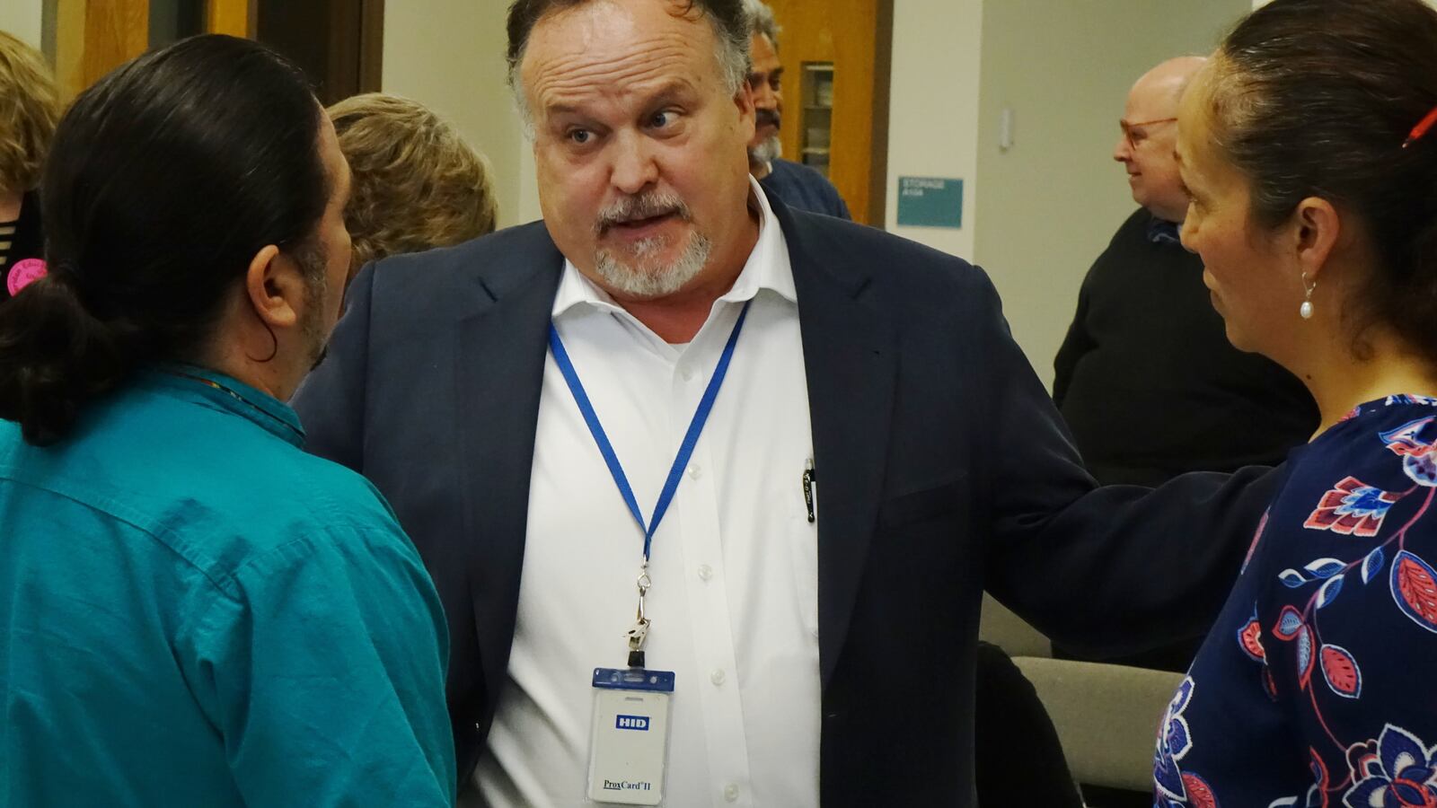 Sheridan School District Superintendent Pat Sandos talks to two people whose backs are to the camera.