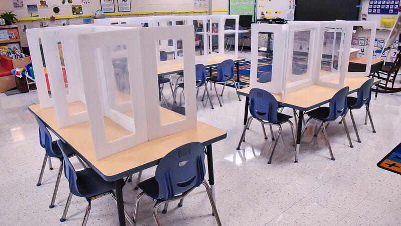 Desks in a classroom are lined with glass partitions to prevent the spread of COVID.