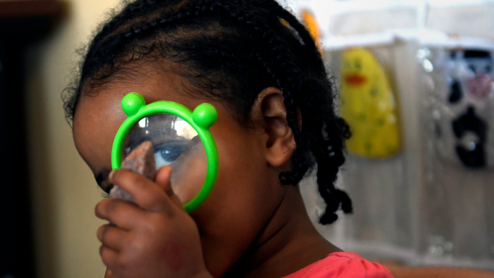 Anna Mandefro, the daughter of Yemi Habte, a MyVillage franchisee in Aurora, looks at rocks through a magnifying glass.
