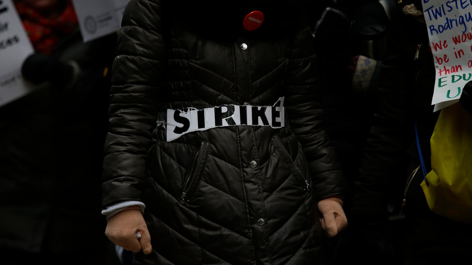 The word 'strike' is taped across a coat as Educators from the Acero charter school network protest during a strike outside Chicago Public Schools headquarters in December