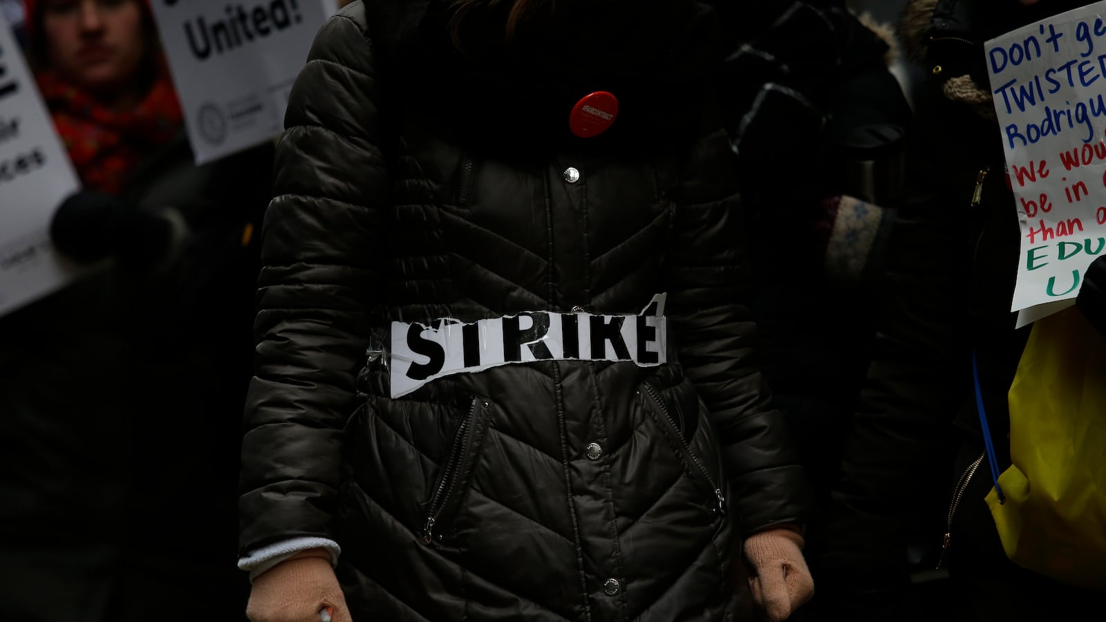 The word 'strike' is taped across a coat as Educators from the Acero charter school network protest during a strike outside Chicago Public Schools headquarters in December