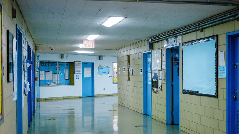 An empty school hallway with beige walls and blue doors