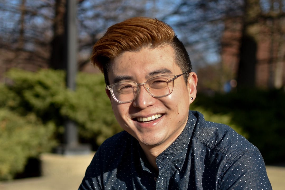 A man wearing glasses and a polka dot shirt smiles for the camera.