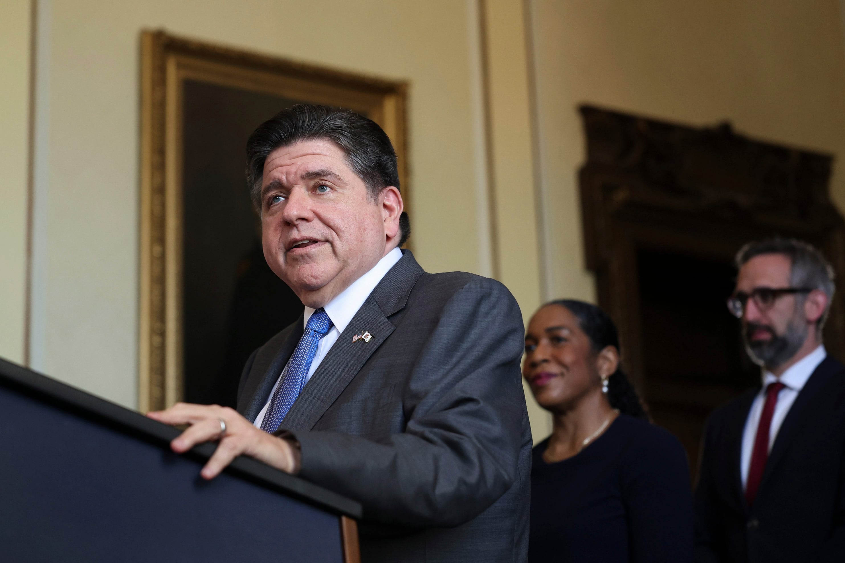 A white male in a suit is speaking at a podium.