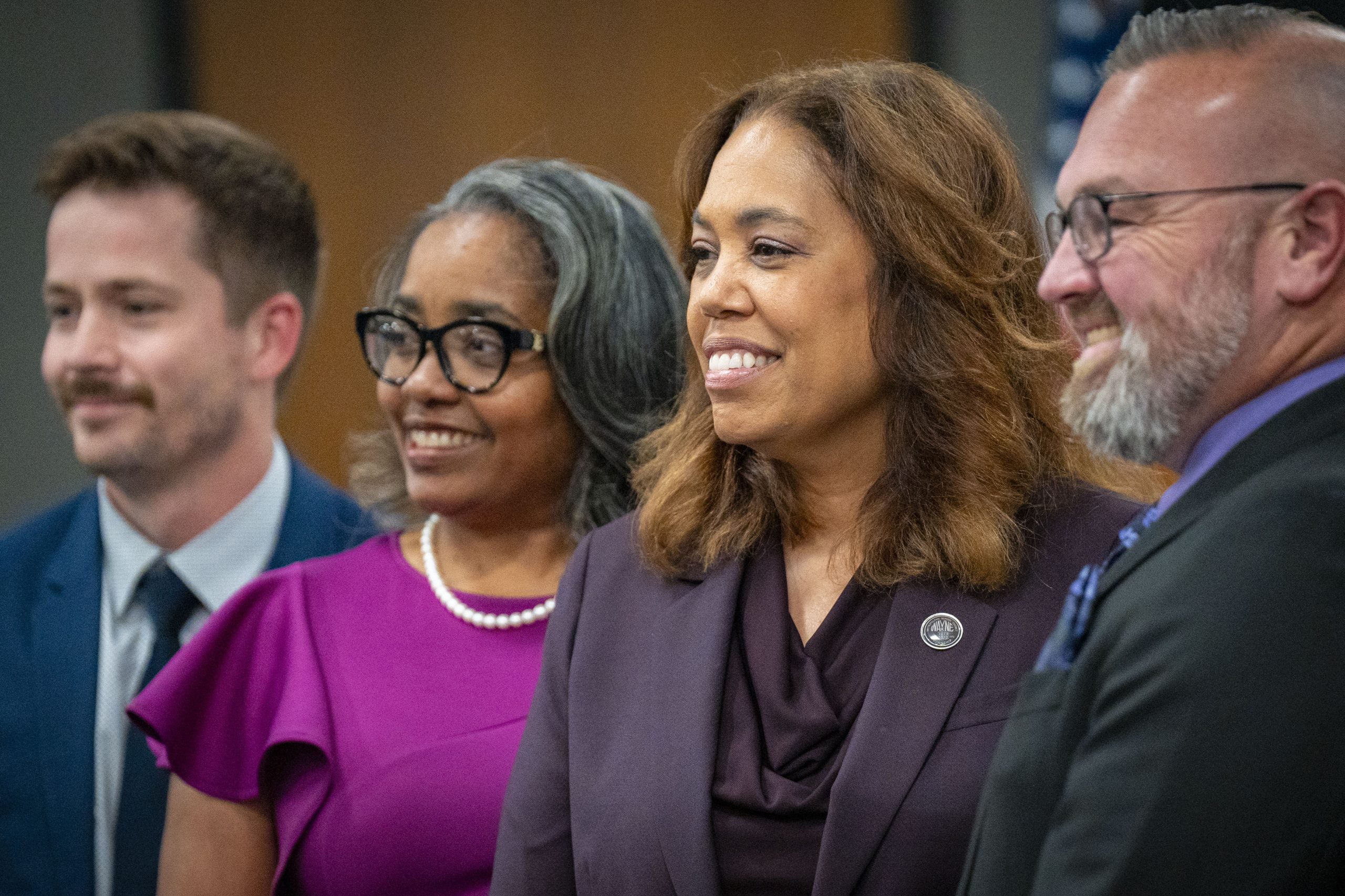 A photograph of four adults standing next to each other smiling and posing for a photograph.