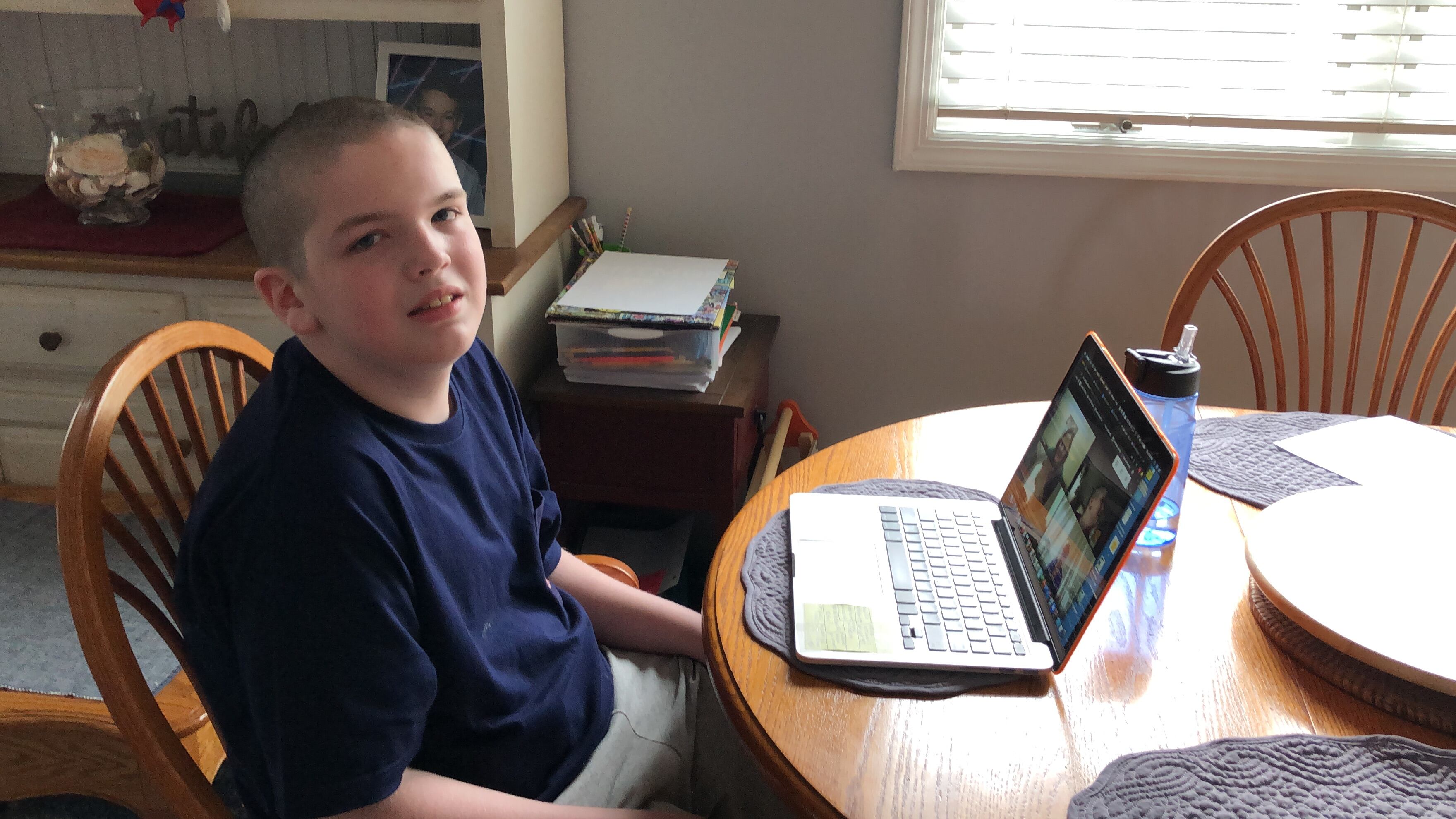 Kristen Collins’ son, Matty, sits at a kitchen table with a laptop.