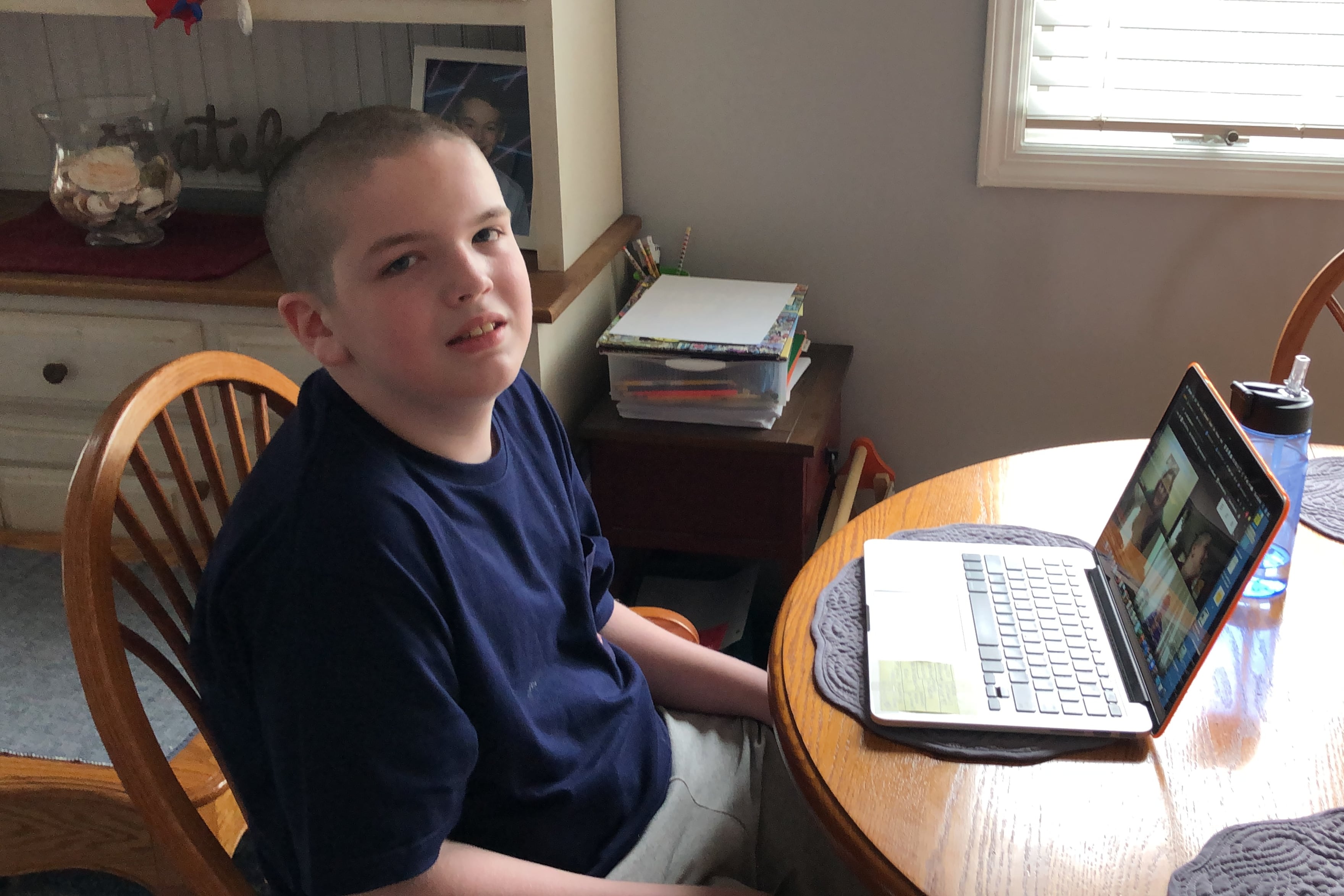 Kristen Collins’ son, Matty, sits at a kitchen table with a laptop.