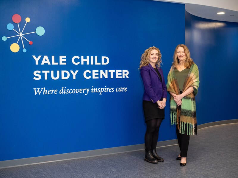 Kathryn Meyer, left, attorney at the Center for Children’s Advocacy, and Christiana Mills, are part of the Yale Child Study Center in New Haven, Connecticut. Two women stand in front of a sign for the Yale Child Study Center and face the camera.