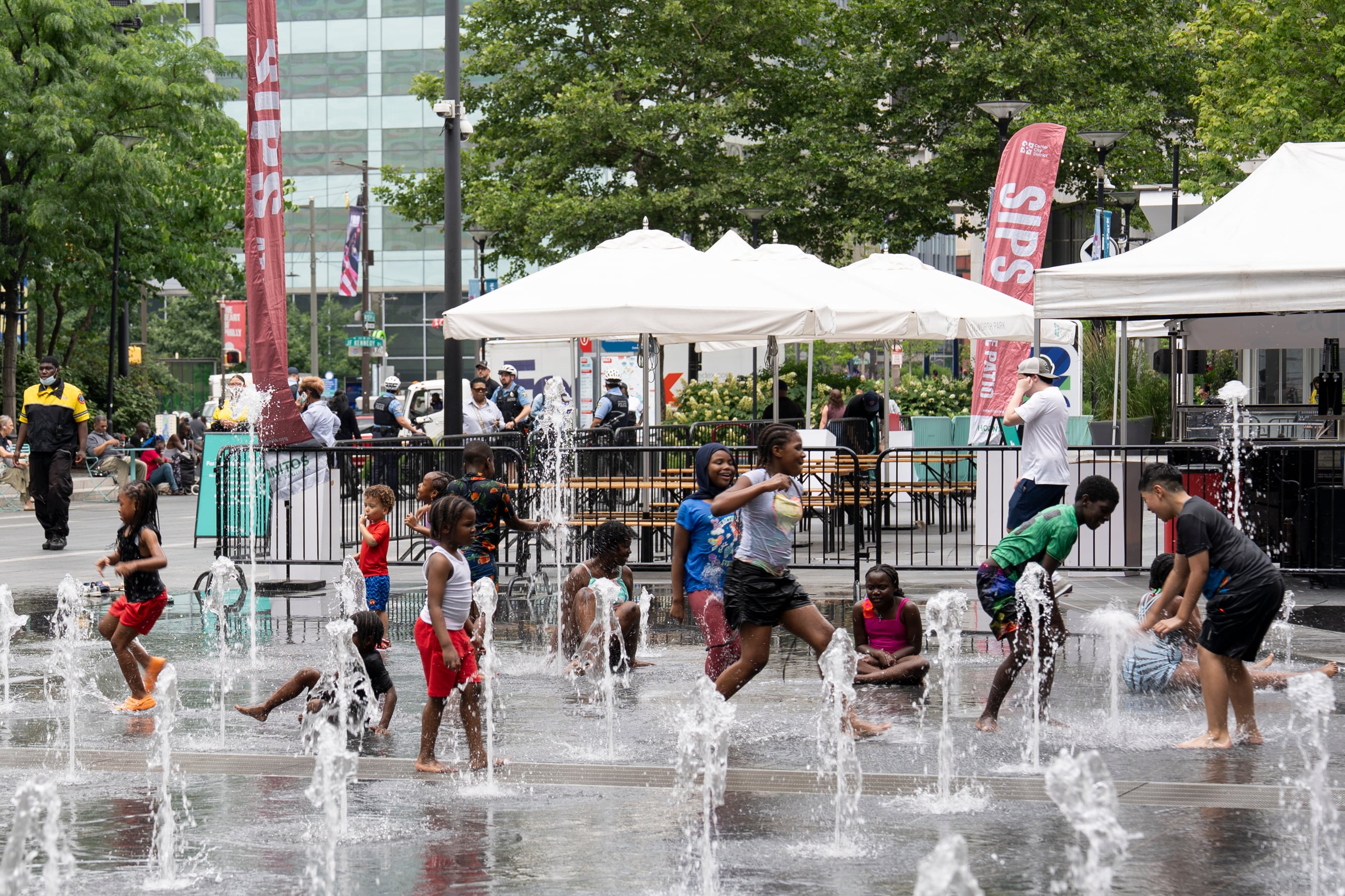 A photograph of a group of children playing at the water fountain.