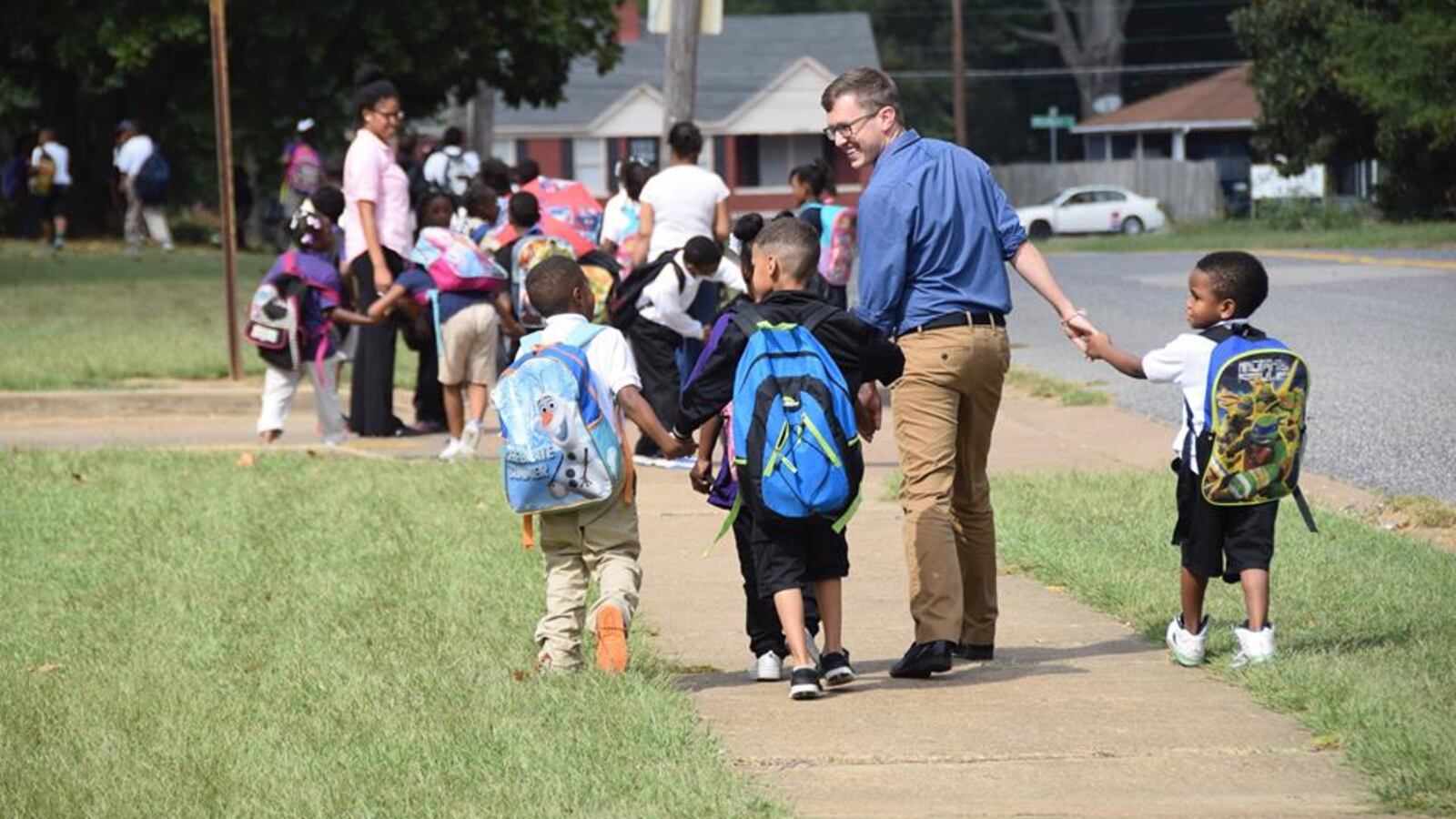 Teacher Carl Schneider walks children home in 2015 as part of the after-school walking program at Whitney Achievement Elementary School in Memphis. This photograph went viral and inspired a First Person reflection from Schneider in 2017.