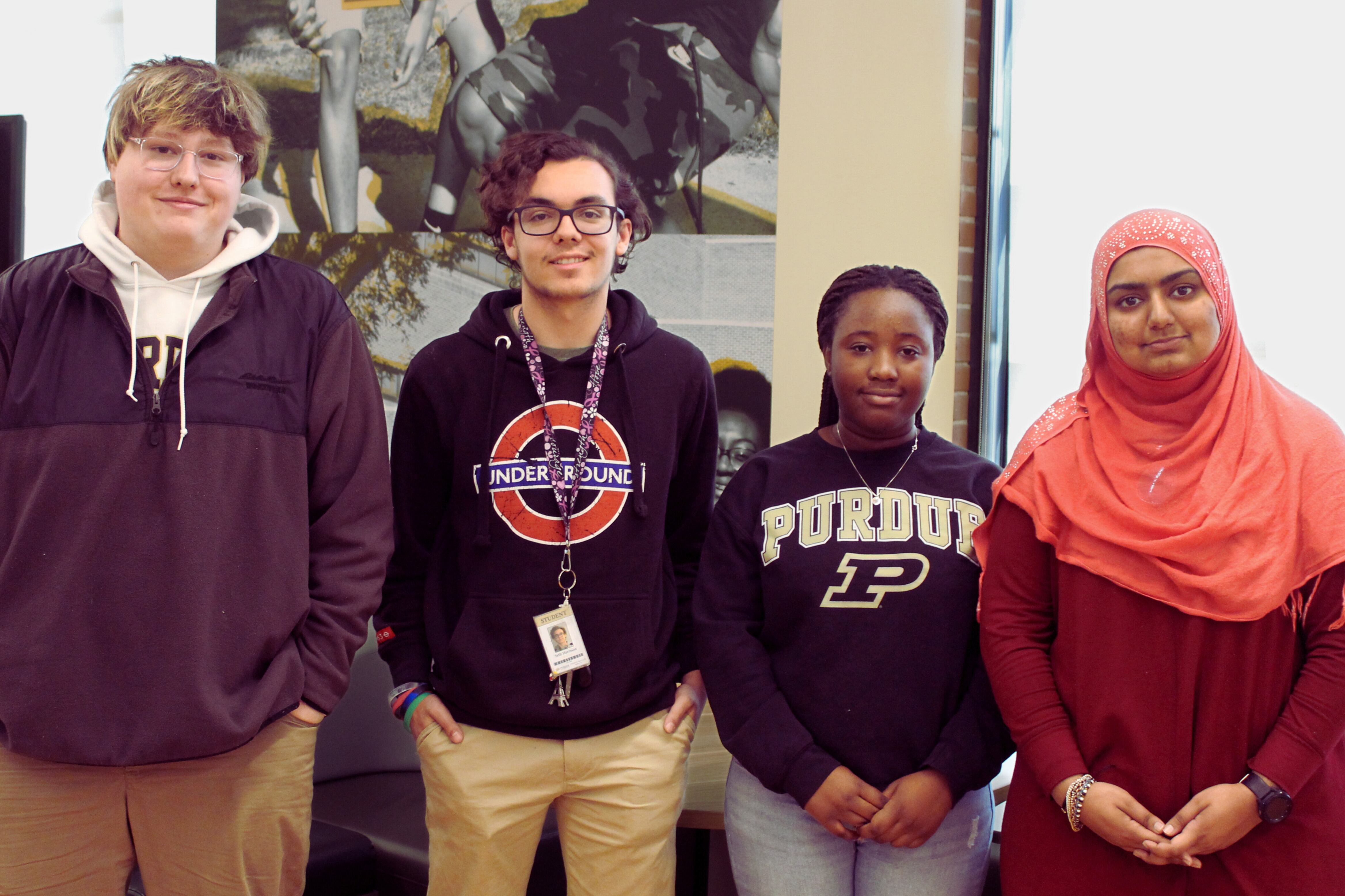 Four high school students stand in a line smiling at the camera.
