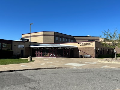 The front entrance of a middle school building on a sunny day with a blue sky above the building.