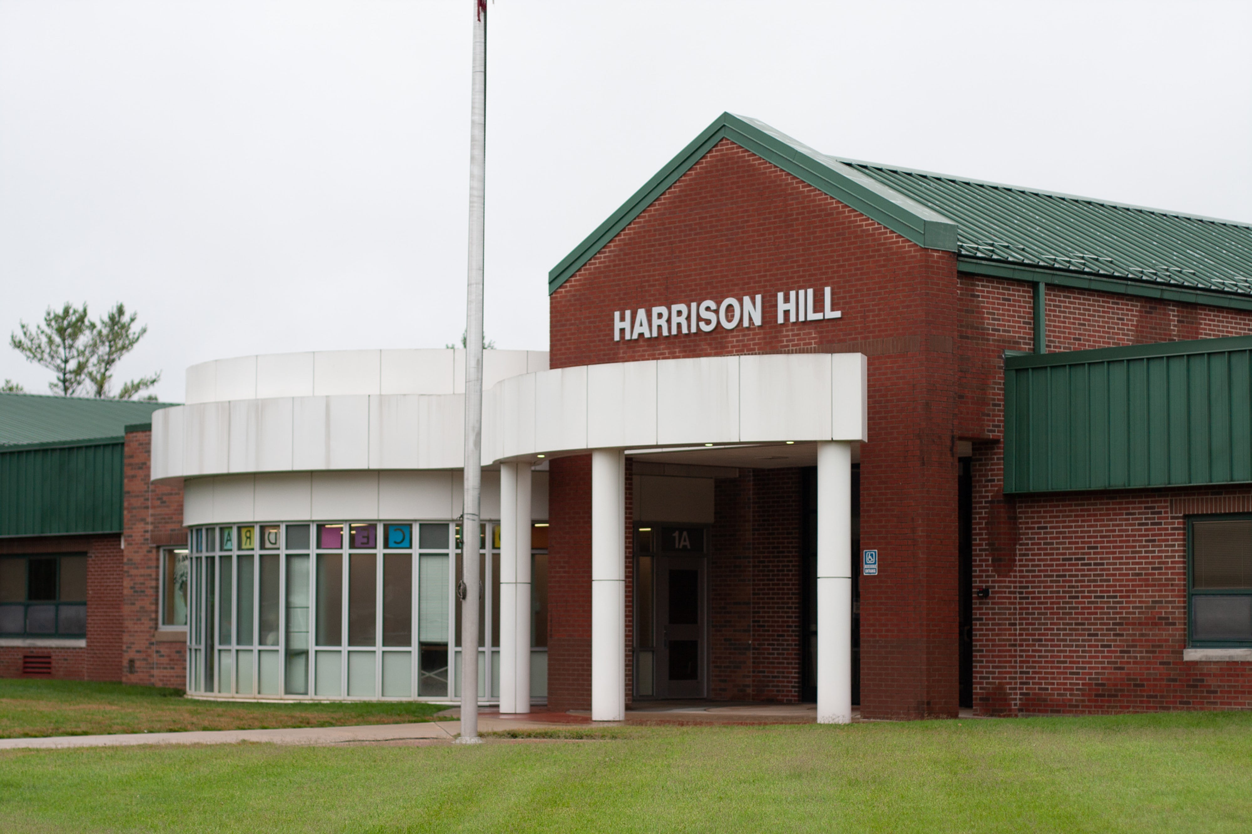 The facade of Harrison Hill Elementary School, a red brick building with a green roof.
