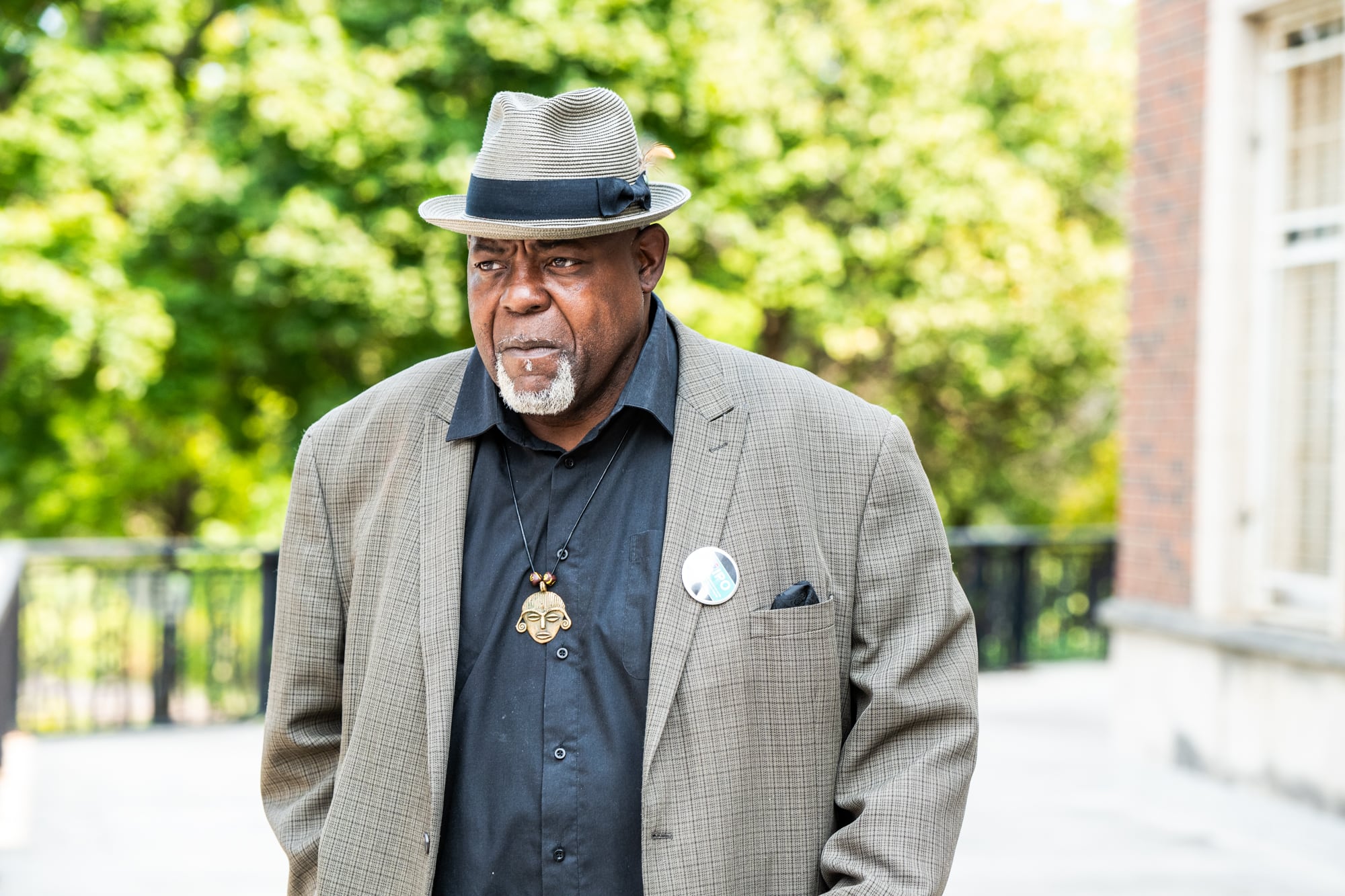 A man in a gray jacket, black shirt and hat.