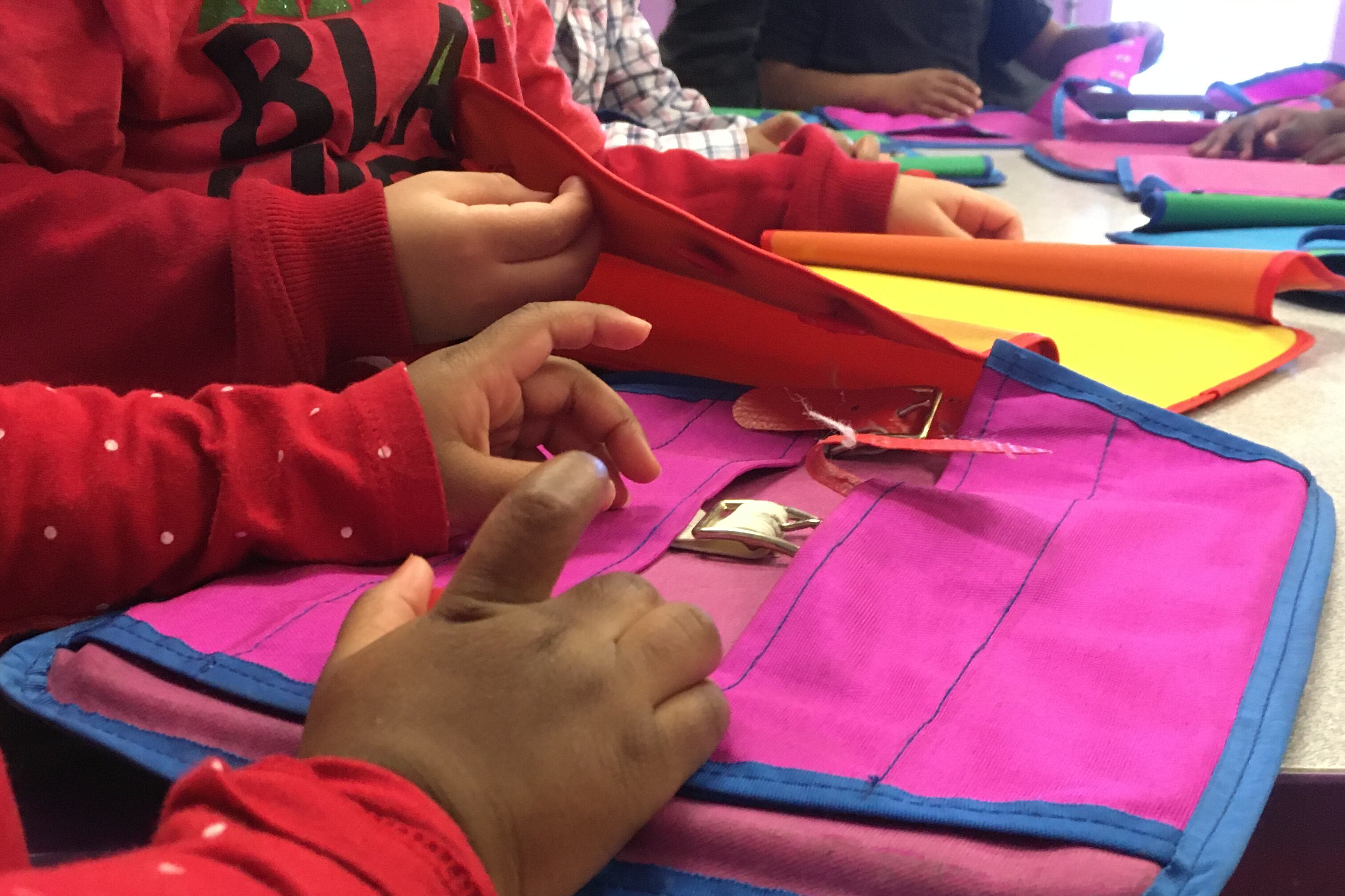 Close-up of a young child opening the clasp of a folder case.