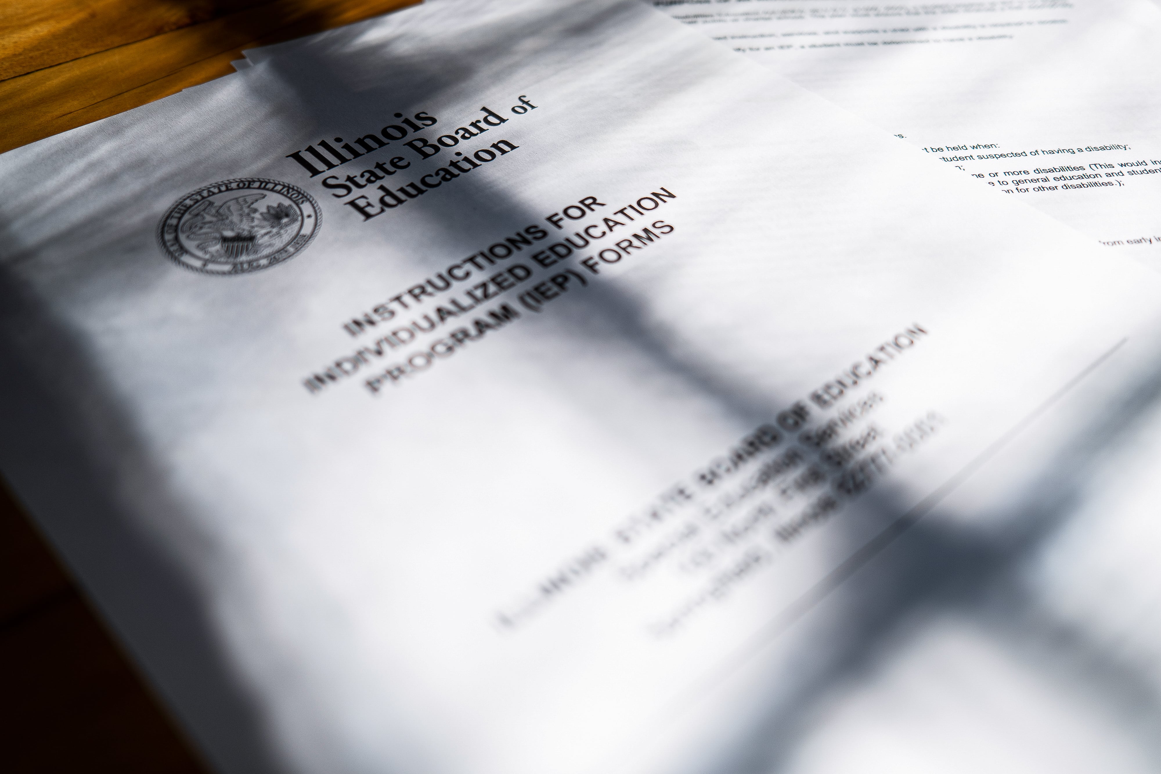 Informational documents from the Illinois State Board of Education on Individualized Education Program forms are partially obscured by shadows.