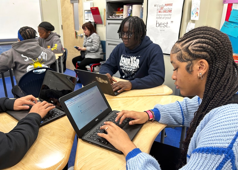Students work at desks in a classroom.