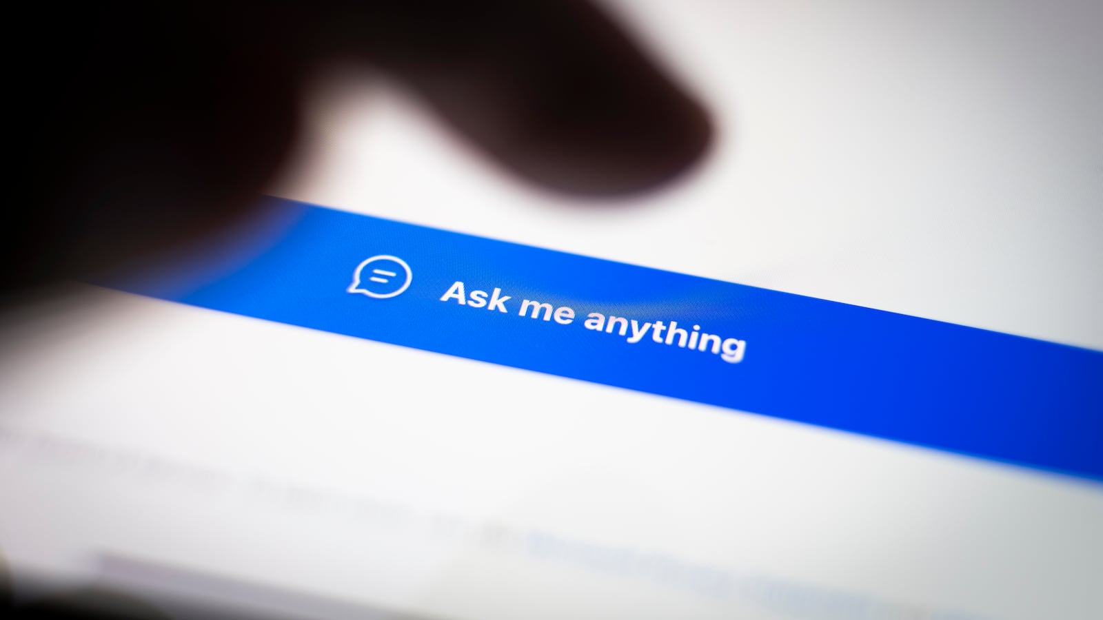 A shadow of a finger on a tablet screen. There’s a button that says, “Ask me anything.”