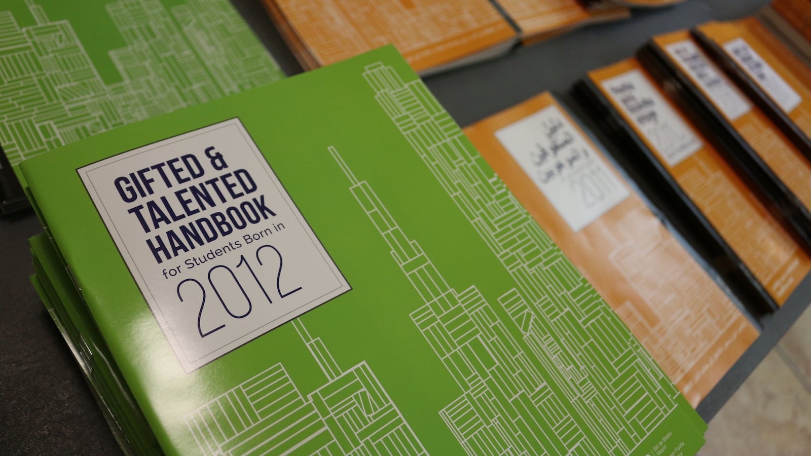 A stack of green and orange guides to Gifted and Talented programs from 2012