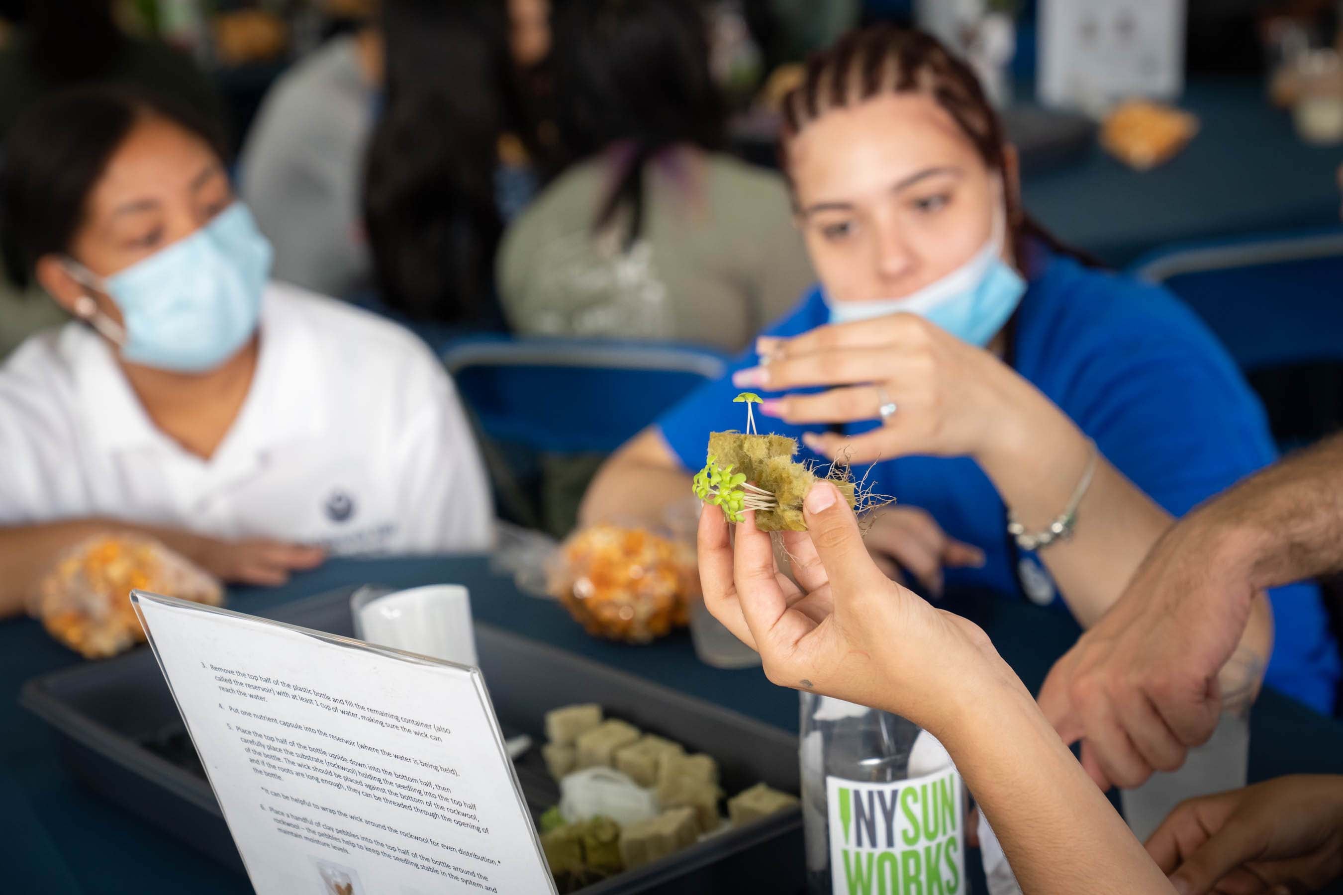 Two students in masks watch a cooking demonstration.