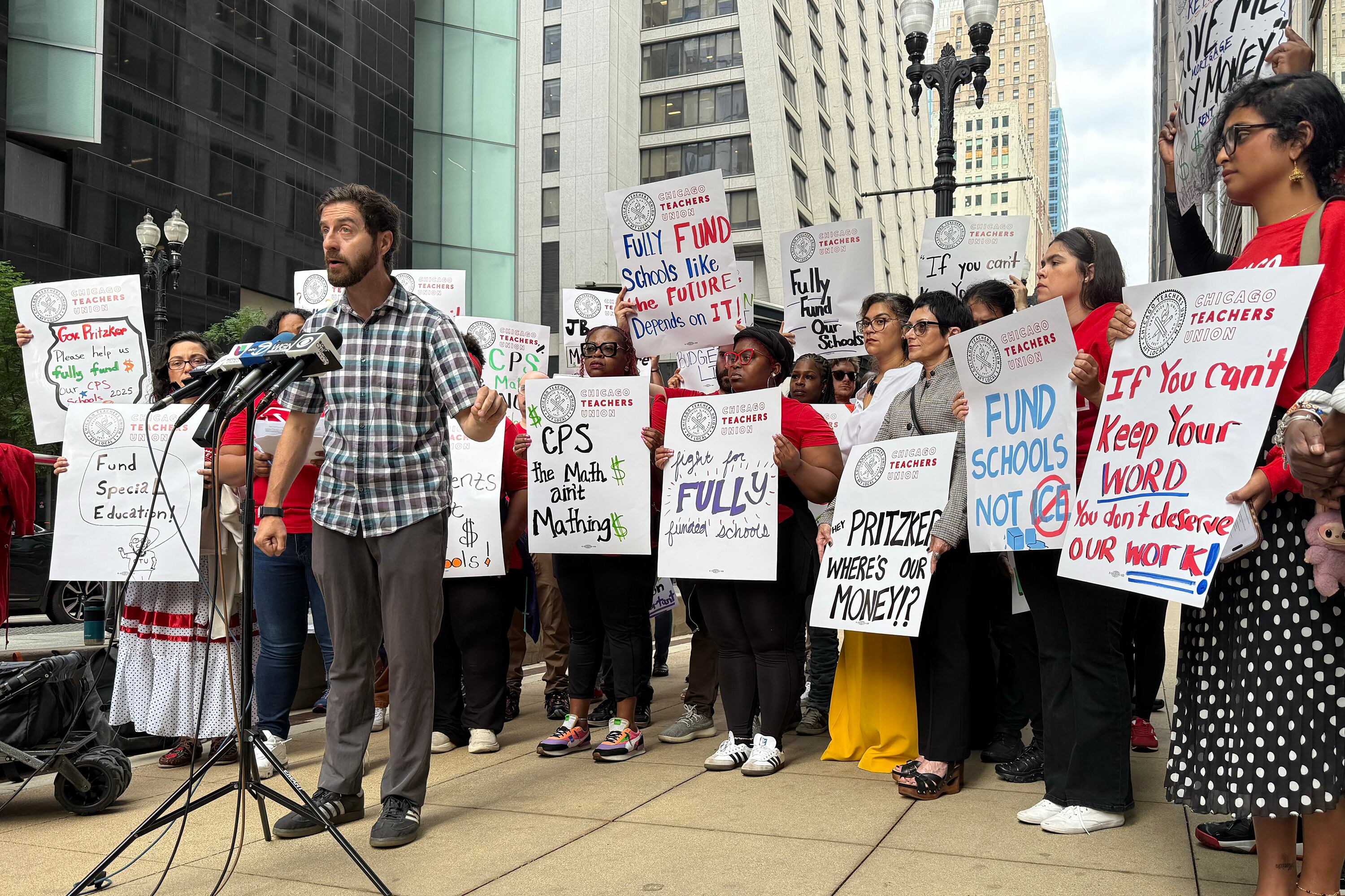 A photograph of a group of people holding large signs outside during a rally.