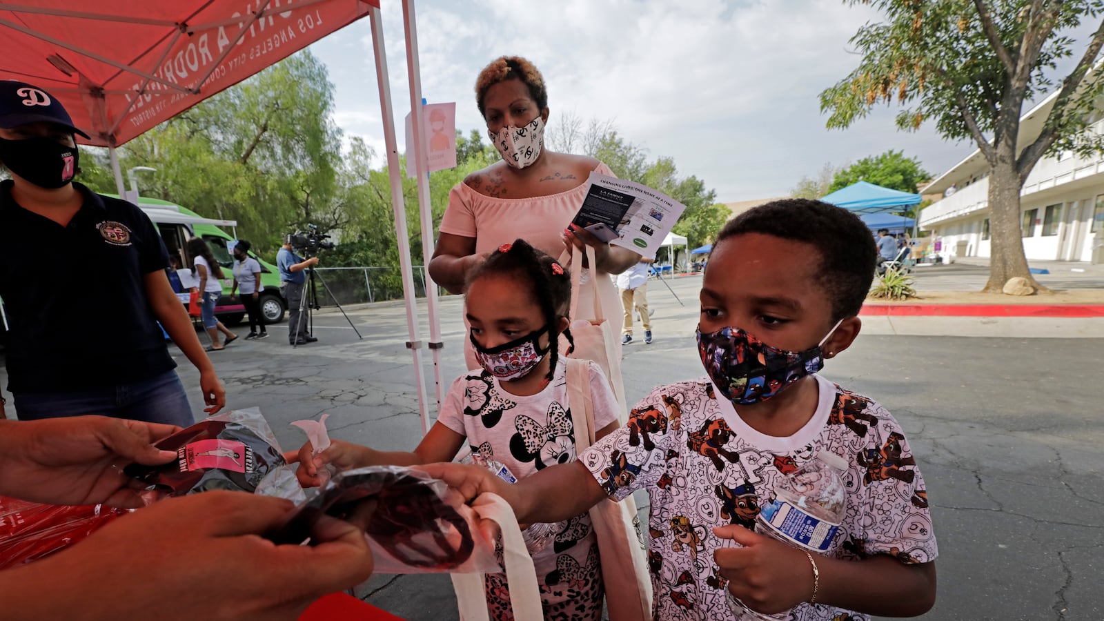 Jazzmin Turman waits on her children Khanukkah, 4, and Shalom, 3, picking up school supplies and masks during a back-to-school fair at the Vagabond Inn in Sylmar, California on Monday, Aug. 17, 2020.