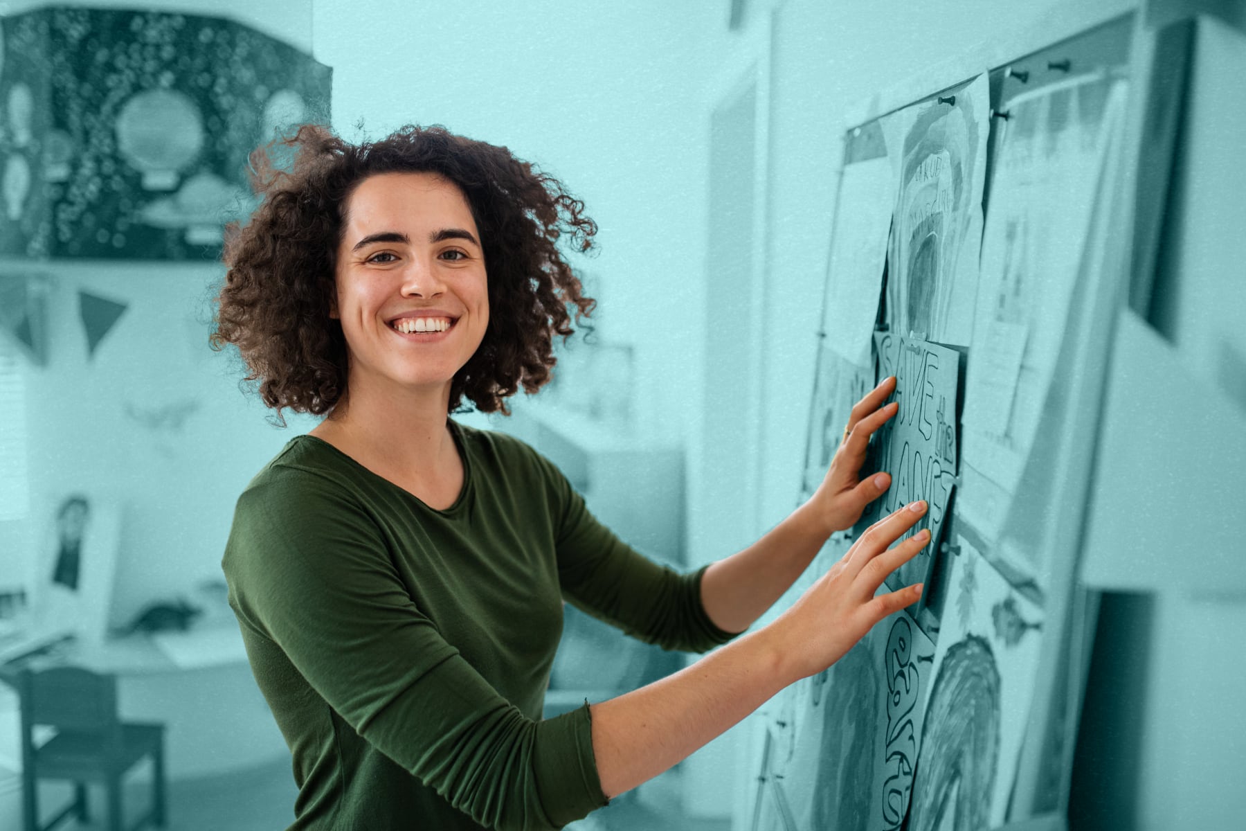 A teacher smiling and decorating their classroom