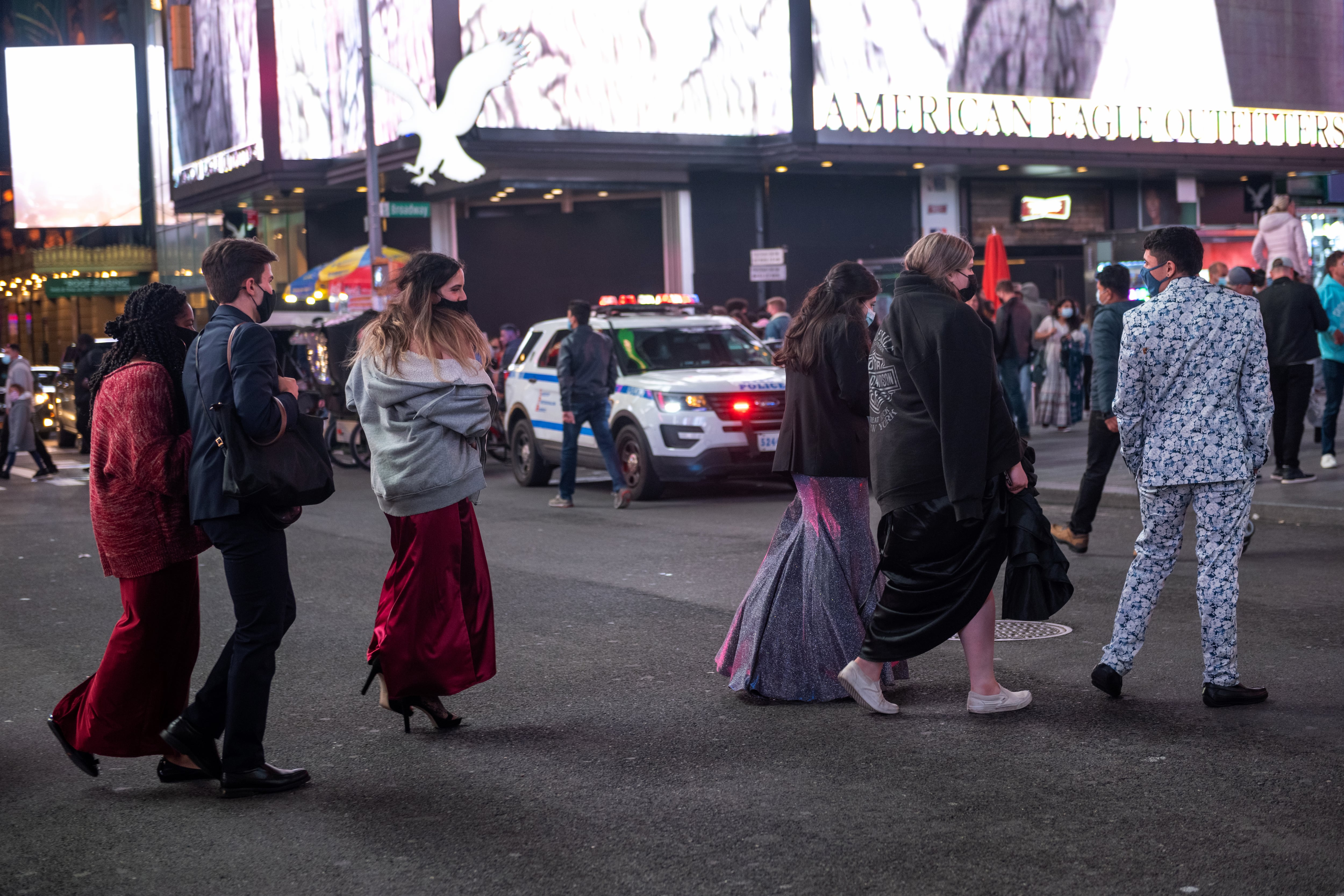 Students walk through New York City’s Times Square wearing prom attire.