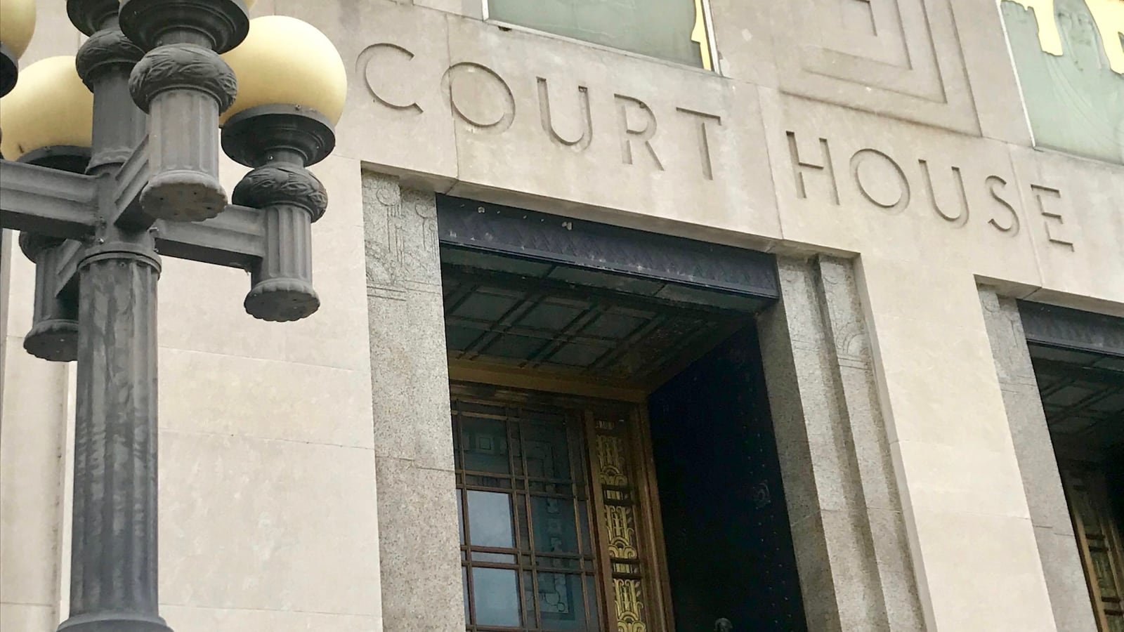 A stone building bearing the etched words “COURT HOUSE” beside a lamppost