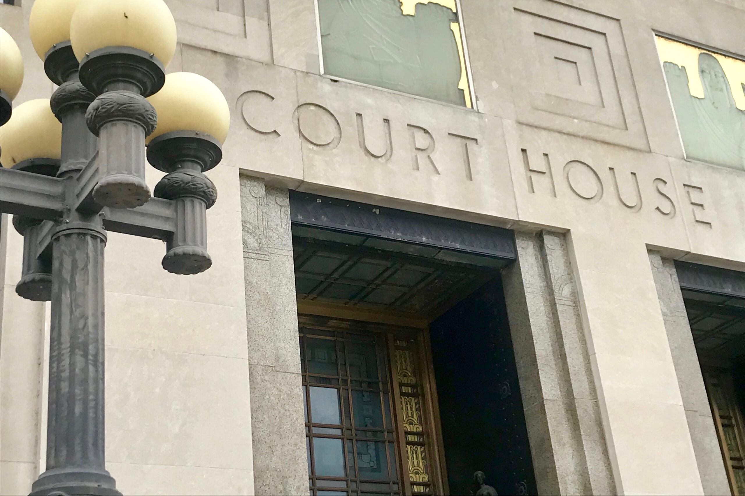 A stone building bearing the etched words “COURT HOUSE” beside a lamppost