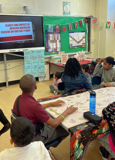 young students in elementary school sit at their desks in a classroom.